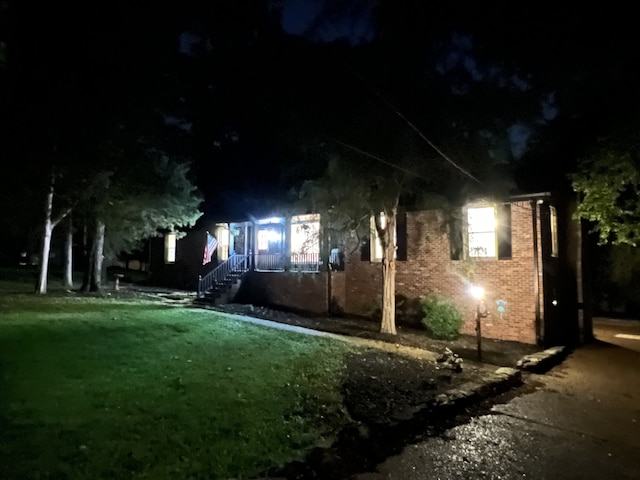 property exterior at night featuring a lawn