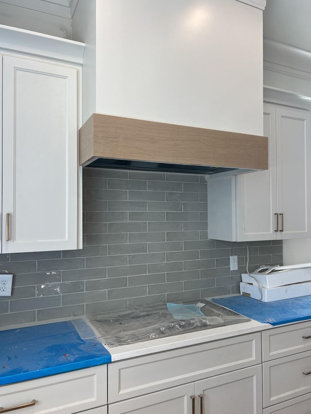 kitchen with tasteful backsplash, white cabinets, and custom exhaust hood