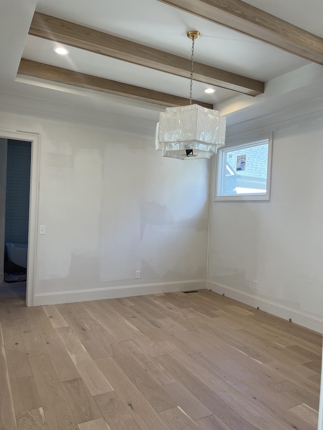 unfurnished dining area featuring beamed ceiling and light wood-type flooring