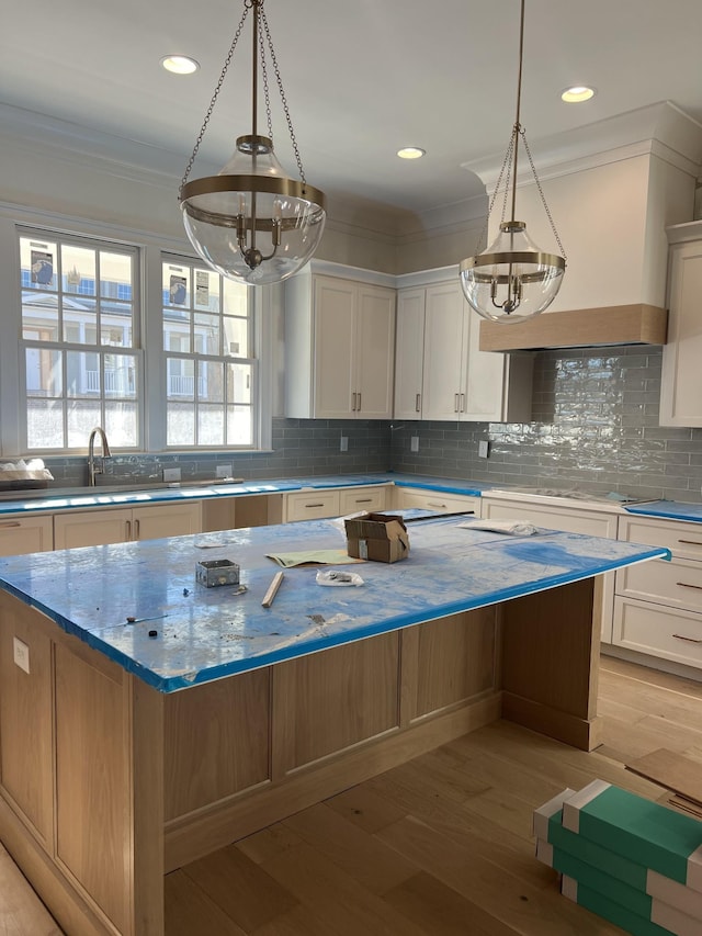 kitchen with a center island, light wood-type flooring, white cabinetry, and crown molding