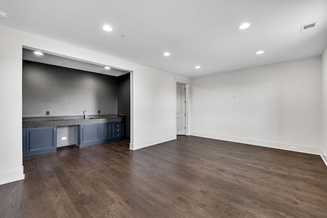 unfurnished living room with bar and dark wood-type flooring