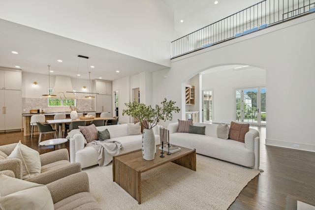 living room with a towering ceiling and dark wood-type flooring