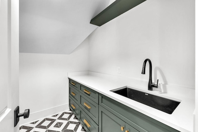 interior space with vaulted ceiling, sink, and green cabinets