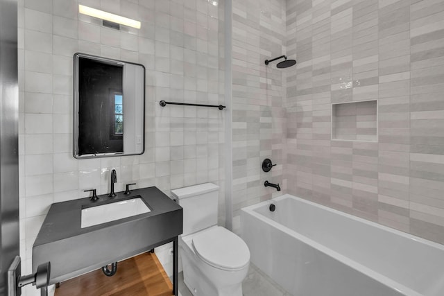 full bathroom featuring toilet, sink, tiled shower / bath, tile walls, and hardwood / wood-style floors