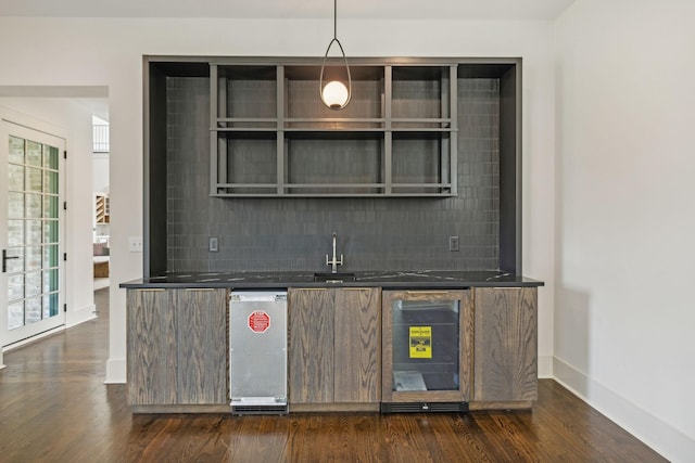 bar with tasteful backsplash, dark hardwood / wood-style floors, sink, and hanging light fixtures