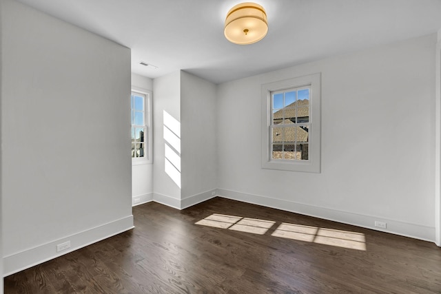 empty room with plenty of natural light and dark hardwood / wood-style floors