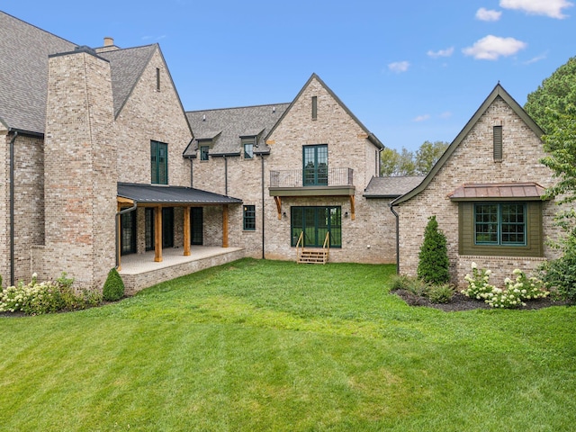 rear view of house featuring a lawn and a patio