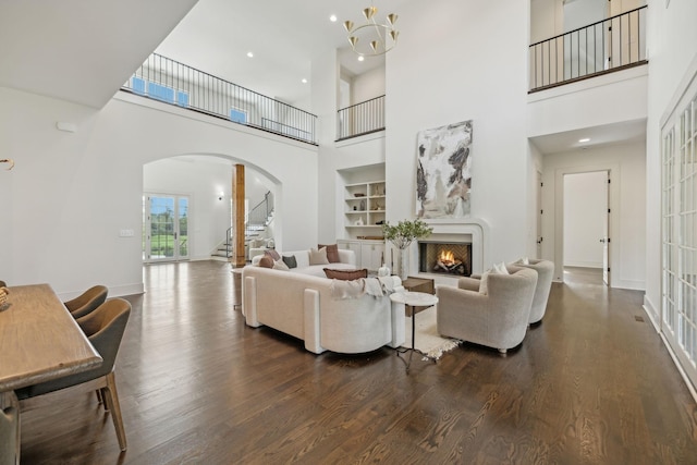 living room featuring dark wood-type flooring, a chandelier, and built in shelves