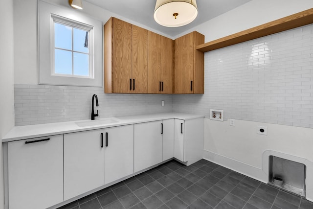 clothes washing area with sink, dark tile patterned floors, electric dryer hookup, hookup for a washing machine, and cabinets