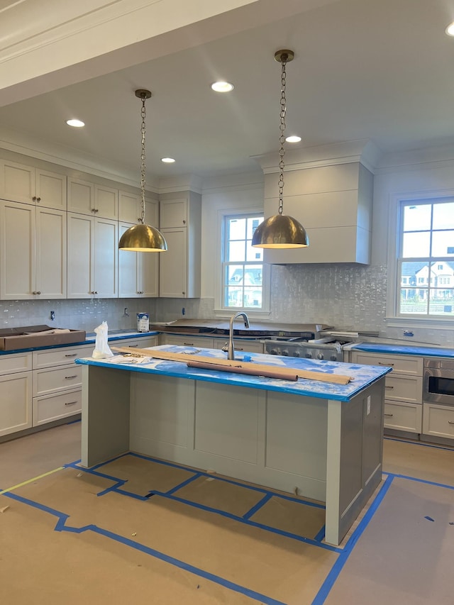 kitchen with sink, a center island with sink, ornamental molding, pendant lighting, and decorative backsplash