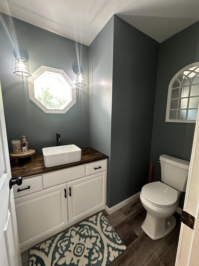 bathroom with toilet, wood finished floors, vanity, and baseboards