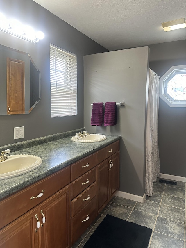 bathroom with double vanity, baseboards, and a sink