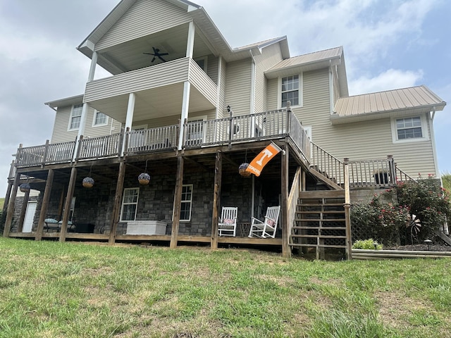 back of property with metal roof, stairway, a wooden deck, and a lawn