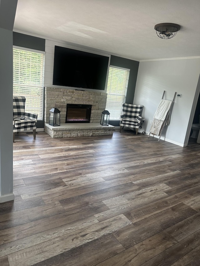 unfurnished living room featuring baseboards, a fireplace, ornamental molding, and dark wood-style flooring