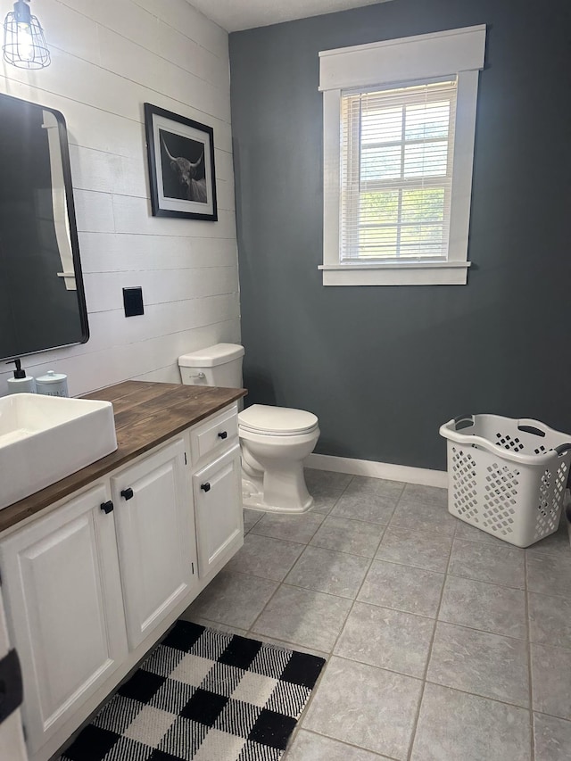 bathroom featuring baseboards, vanity, toilet, and tile patterned floors