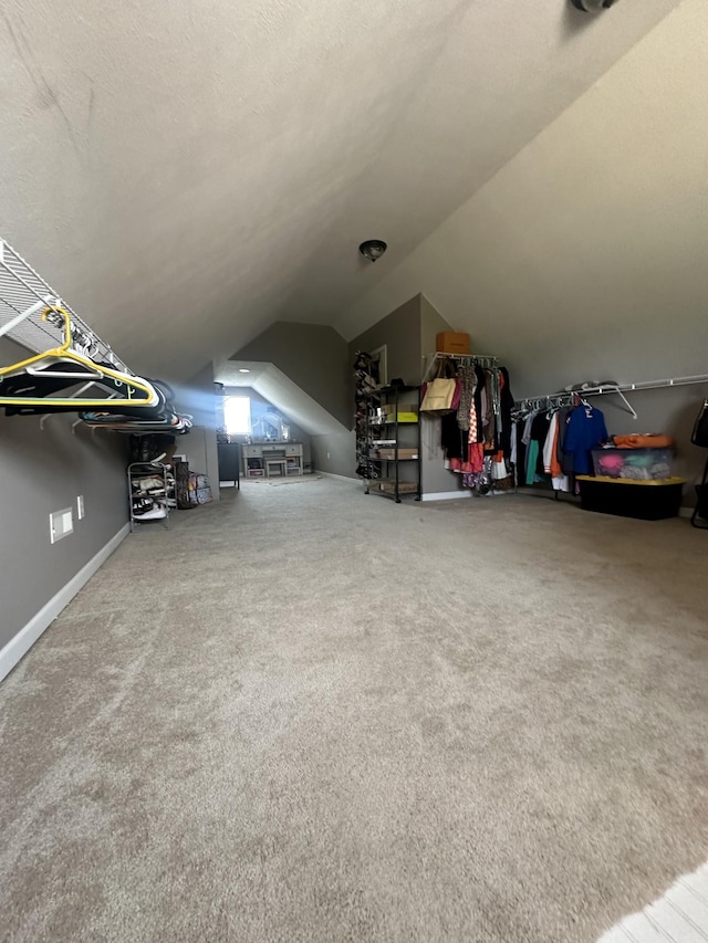 interior space featuring lofted ceiling, baseboards, a textured ceiling, and carpet flooring