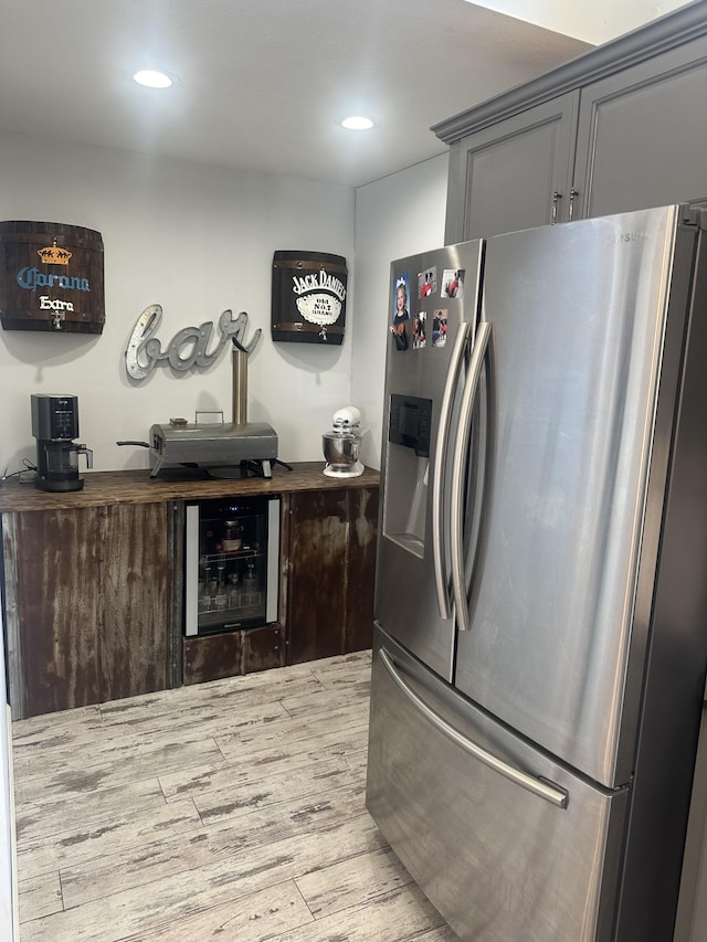 kitchen with recessed lighting, beverage cooler, light wood-style flooring, and stainless steel fridge with ice dispenser