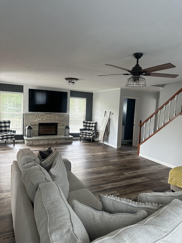 living room with dark wood-style floors, a wealth of natural light, a stone fireplace, and stairs