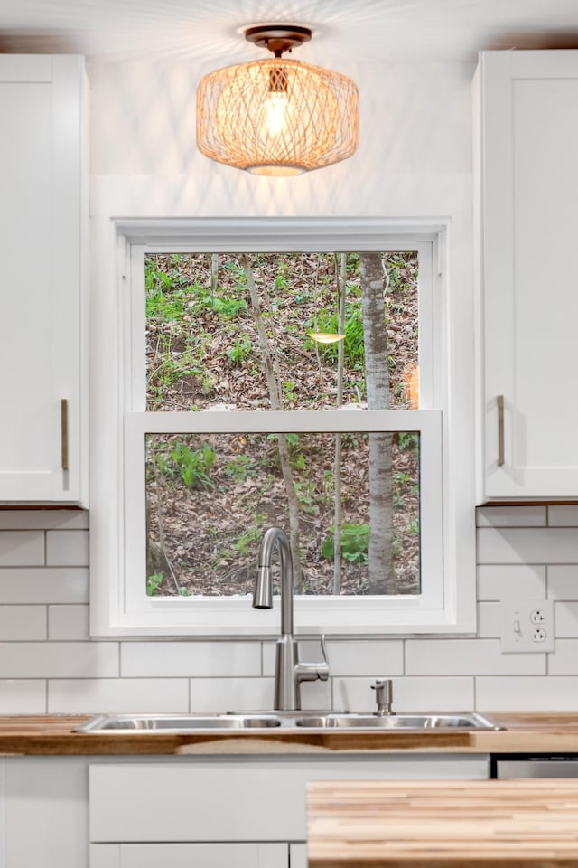 kitchen featuring sink, white cabinets, and backsplash