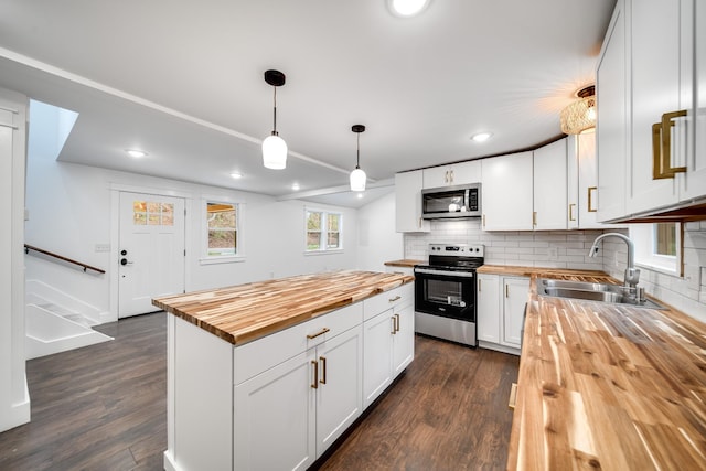 kitchen with butcher block countertops, sink, white cabinetry, hanging light fixtures, and stainless steel appliances