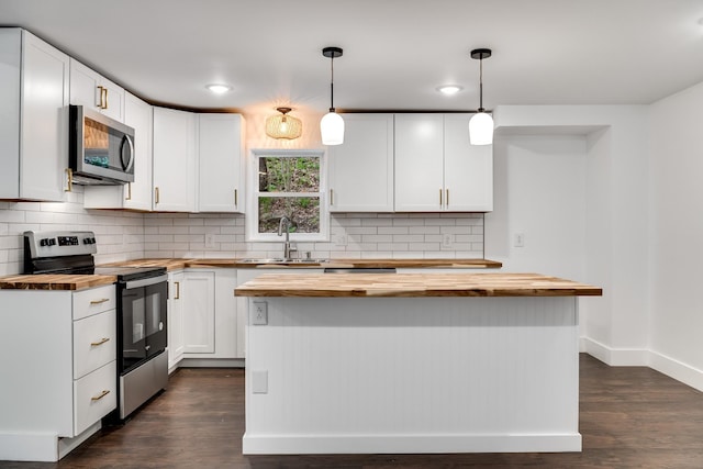 kitchen featuring stainless steel appliances, white cabinetry, hanging light fixtures, and butcher block counters