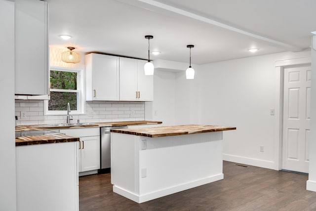 kitchen with hanging light fixtures, butcher block counters, sink, and white cabinets