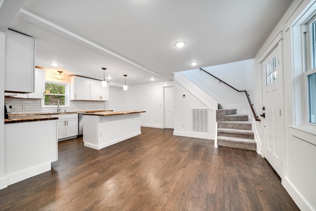 kitchen featuring white cabinetry, a center island, pendant lighting, and wood counters