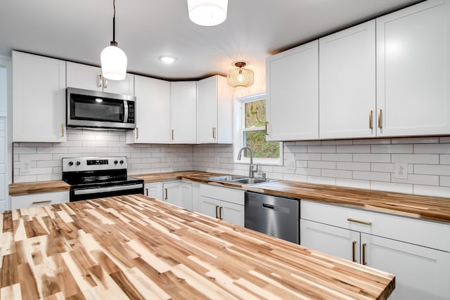 kitchen with pendant lighting, sink, white cabinets, wooden counters, and stainless steel appliances