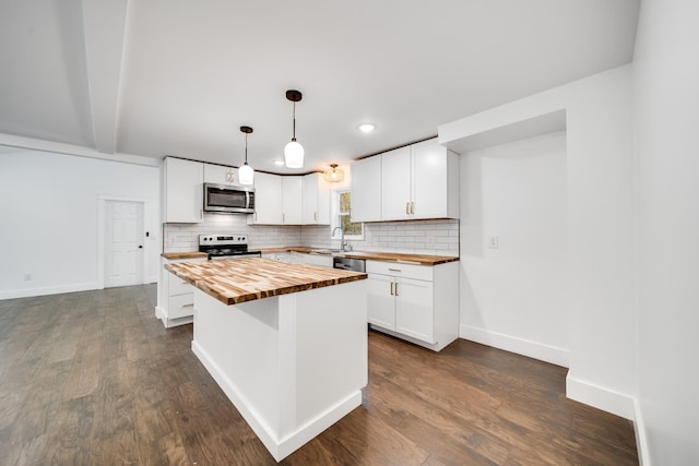 kitchen with stainless steel appliances, hanging light fixtures, white cabinets, and wood counters