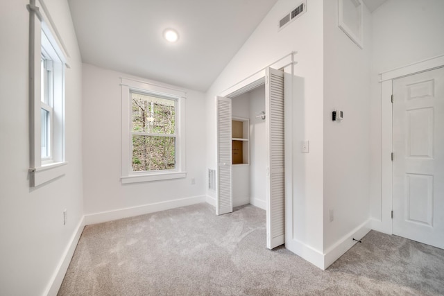 interior space with vaulted ceiling and light carpet