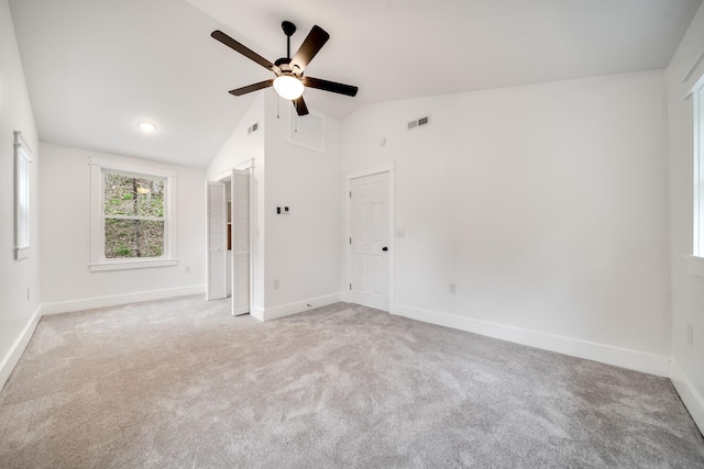 carpeted spare room featuring vaulted ceiling and ceiling fan