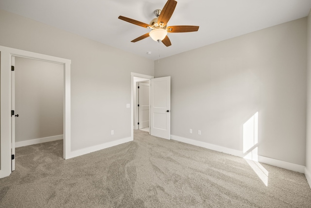 unfurnished bedroom featuring ceiling fan, light colored carpet, and a walk in closet