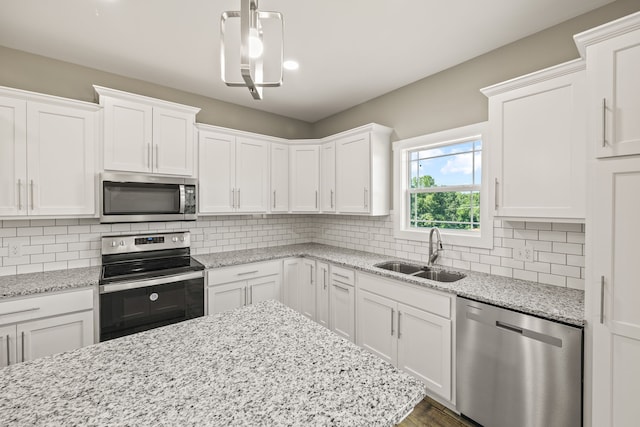 kitchen featuring white cabinets, stainless steel appliances, hanging light fixtures, and sink