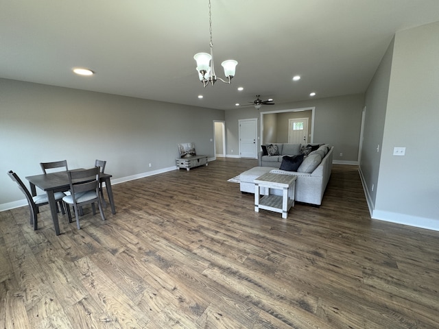 living room with ceiling fan with notable chandelier and dark wood-type flooring