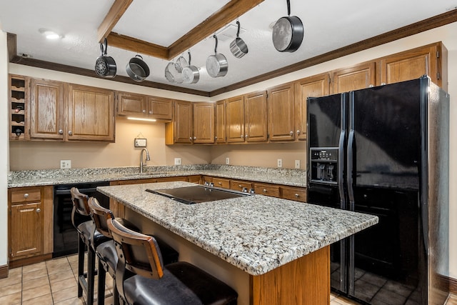 kitchen with black appliances, crown molding, light stone counters, a kitchen island, and light tile patterned floors