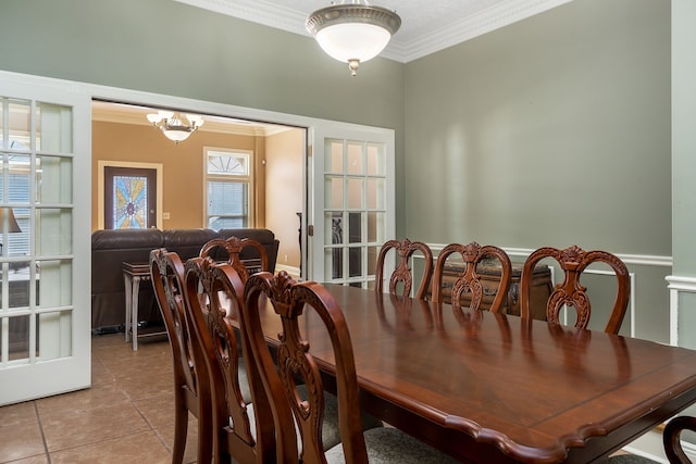 dining area featuring crown molding, a notable chandelier, and light tile patterned floors