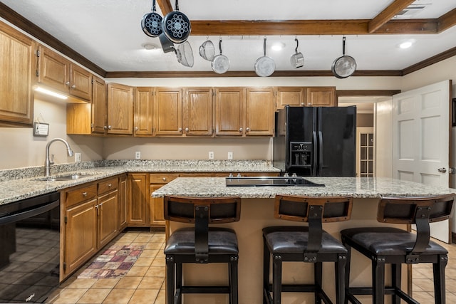 kitchen with black appliances, ornamental molding, light stone counters, a kitchen island, and light tile patterned floors