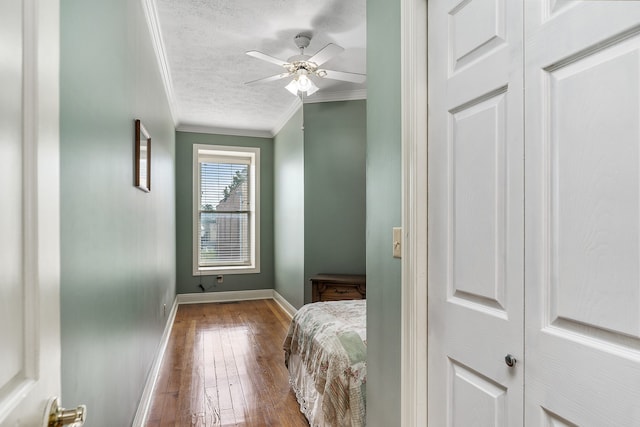 corridor featuring hardwood / wood-style flooring, a textured ceiling, and ornamental molding