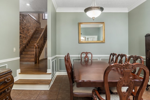 tiled dining room with a textured ceiling, brick wall, and ornamental molding