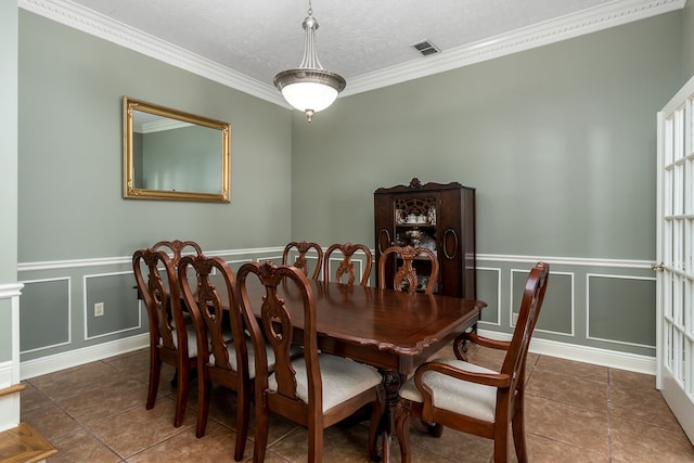 dining room with a textured ceiling, crown molding, and dark tile patterned flooring