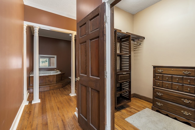 spacious closet with light hardwood / wood-style floors and decorative columns