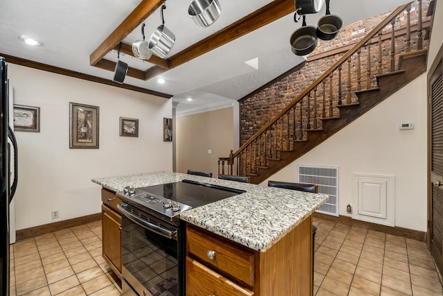 kitchen with beamed ceiling, black range with electric cooktop, light tile patterned floors, light stone countertops, and a center island