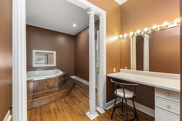 bathroom with vanity, a bathtub, hardwood / wood-style flooring, and crown molding