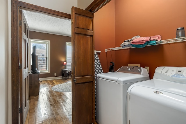 laundry area with a textured ceiling, crown molding, light wood-type flooring, and washing machine and clothes dryer