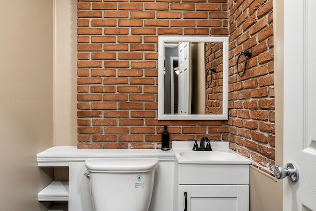 bathroom with vanity, brick wall, and toilet