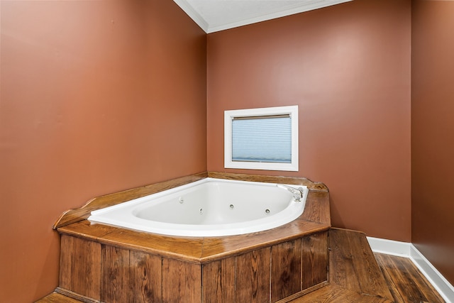 bathroom with ornamental molding, hardwood / wood-style floors, and a bath