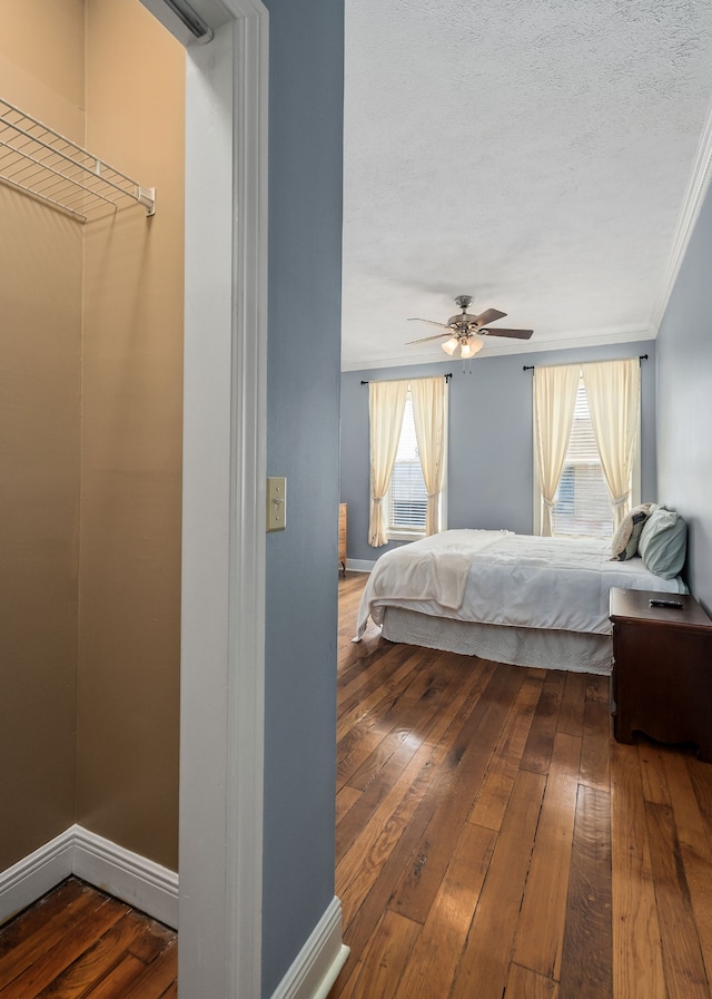 bedroom with ornamental molding, wood-type flooring, ceiling fan, and a textured ceiling