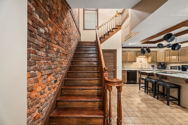 stairway with sink, brick wall, and light tile patterned floors