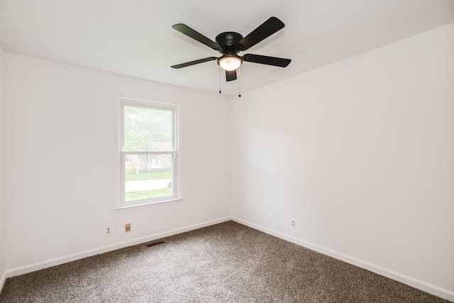 carpeted spare room featuring ceiling fan, visible vents, and baseboards