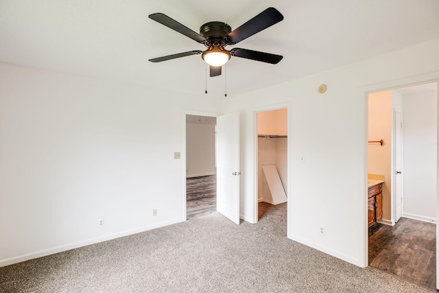 unfurnished bedroom featuring carpet floors, a walk in closet, a closet, ceiling fan, and baseboards